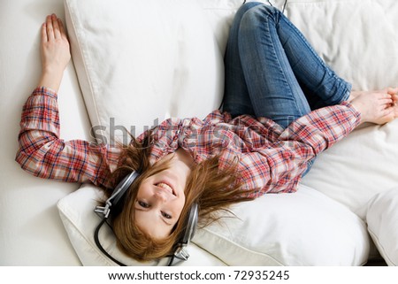 Young attractive woman listening to music on sofa