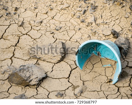 Bucket in cracked soil in dry river from drought, Global warming concept
