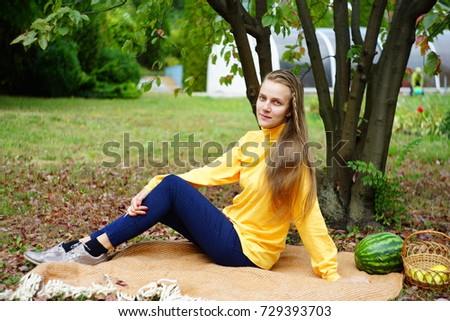 Beautiful woman relax in the garden, sits on a wool blanket. beauty of nature, autumn park. Round shape wicker basket, daylight illuminates plants. picnic in the village, fresh air. horizontal banner