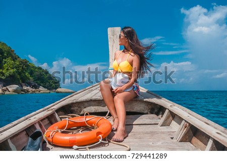 Traveler woman in bikini relaxing on wooden boat and looking destination island , Andaman sea, Mu Koh Surin national park, Phangnga, Travel in Thailand, Summer and vacation trip