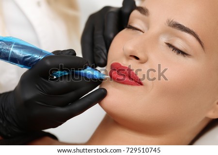 Healthy Spa: Young Beautiful Woman Having Permanent Make-up (Tattoo) on her Lips. Close-up Royalty-Free Stock Photo #729510745