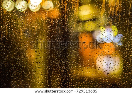 Blurry with raining on the glass and colorful in the background.