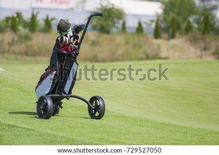 Closeup of golf trolley with clubs in golf course. Trolley on the fairway 