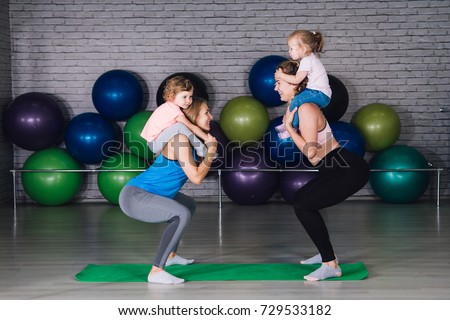 Two young sports mom and baby girls do exercises together in the gym. Parent and child healthy development, fitness and relaxation. Healthy lifestyle concept photo. Toning. Royalty-Free Stock Photo #729533182
