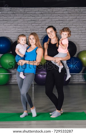 Two young sports mom and baby girls do exercises together in the gym. Parent and child healthy development, fitness and relaxation. Healthy lifestyle concept photo. Toning.
