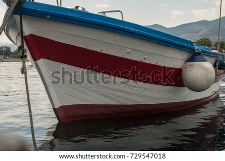 The fishing boat is white and red, empty, on the water