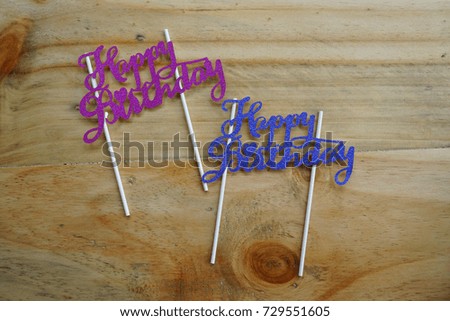Top or flat lay view of birthday props happy birthday with purple and blue happy birthday writing on a wooden background flat lay. Birthday parties text and props.