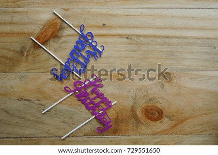 Top or flat lay view of birthday props happy birthday with purple and blue happy birthday writing on a wooden background flat lay. Birthday parties text and props.