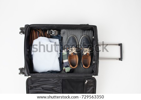 To collect things into a large black suitcase on a trip. An empty space to insert text. Royalty-Free Stock Photo #729563350