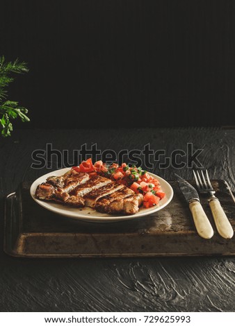 pork steak with tomatoes on a white plate
