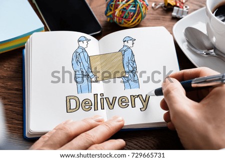 Close-up Of A Person's Hand Drawing Delivery Concept With Movers Carrying Container On Notebook