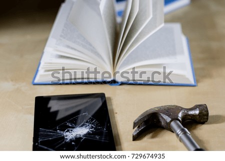 Heap of books reading on a wooden table. Beside lies and tablet. Black background.