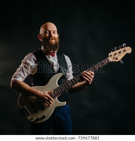 adult bearded man enthusiastically playing guitar on a black background