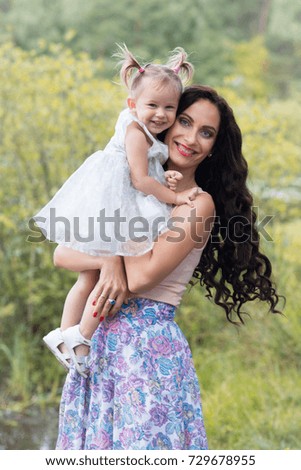 True maternity: beautiful mother with cute little daughter smiling and hugging in the forest in summer