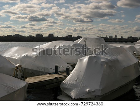 White-covered boats , during the winter, at the wharf of the Charles River in Cambridge, Massachusetts