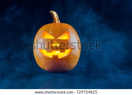 Halloween pumpkin with candle on smoked and dark background