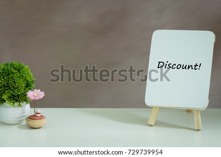 Business concept. Discount sign on mini whiteboard on white table with decoration. Isolated background.