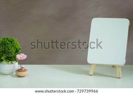 Blank mini whiteboard on white table with flower decoration. Isolated background.