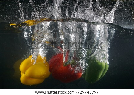 paprika red yellow and green splash in water on black background, 