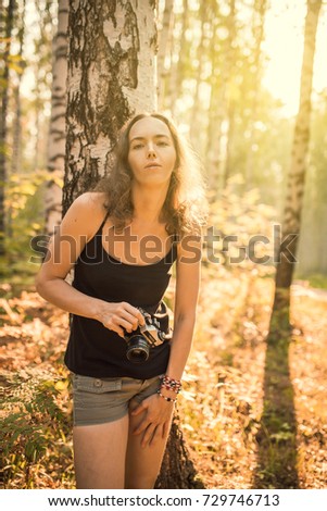 autumn park, a nice sunny day - beautiful young woman with vintage camera makes pictures