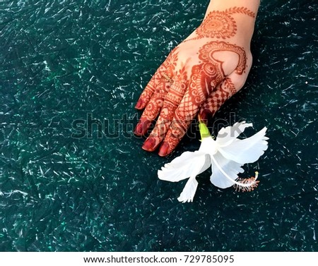 Mehndi hands with white hibiscus flower on green texture background