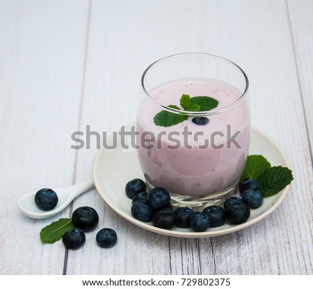 Glass with blueberry yogurt and fresh berries on a table