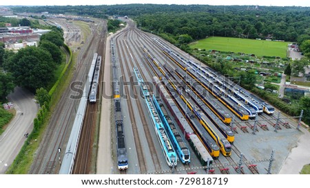 Aerial photo of railroad hub or railway terminal showing two trains passing by also showing different trains parked next to each other on the rail tracks