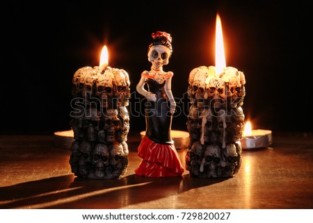Halloween: figures of single skeletons of the woman against the background of the burning candles in the form of skeletons