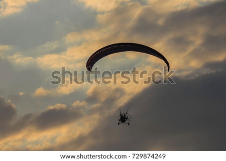 The paraglider hovers in the sky high above the clouds