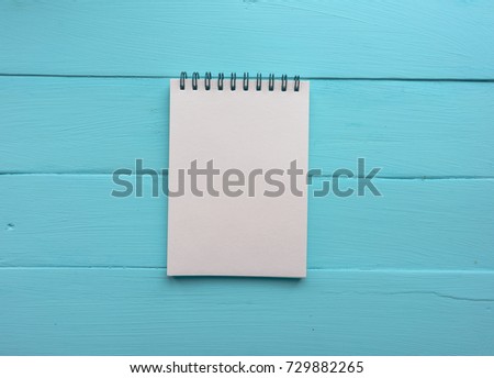 Notebook with a spring. Bright blue, turquoise surface. Painted Board. Close-up with copy space. Top view