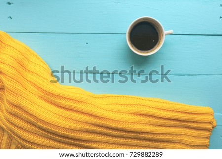 Cup of coffee and yellow sweater. Bright blue, turquoise surface. Painted Board. Close-up with copy space. Top view