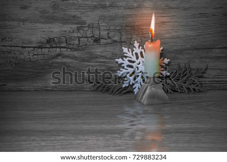 Christmas and new year background. Burning candle on the base of the pyramid healing stone and with reflection on wooden vintage background in black and white