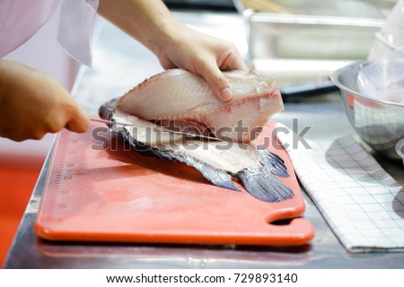 cut fish fillet in a fish shop, chef cutting red fish in the kitchen Royalty-Free Stock Photo #729893140