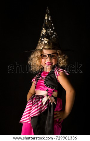 Vertical picture, isolated on black, cute caucasian blonde little girl in black dress with pink stripes, black scull hat and glasses 