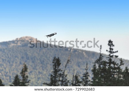 Modern black Remote control Drone or Quadcopter flying at forest background at strong wind