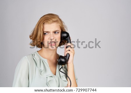 young woman holds a fixed telephone on a gray background                               