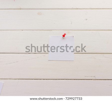 White square sheet of paper pinned to wooden boards. White-painted surface in a rustic style. Close-up. The top view. Background with copy space