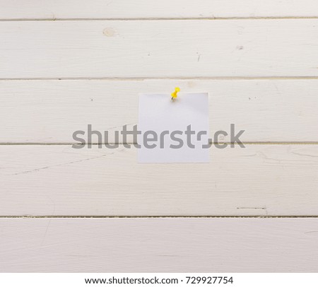 White square sheet of paper pinned to wooden boards. White-painted surface in a rustic style. Close-up. The top view. Background with copy space