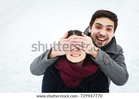 young beautiful enamored couple in winter hugging in snow, together