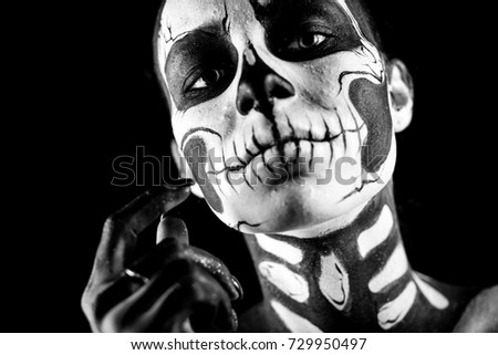 Isolated on black, closeup picture, attractive young brunette caucasian woman with scull body art, grey eyes, languid look, look at camera, hand near her face