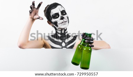 Isolated on white, closeup picture, young brunette caucasian pretty woman with scull body art holds green beer bottle, grey eyes, scares, look at camera