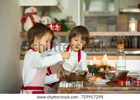 Two sweet children, boy brothers, preparing gingerbread cookies for Christmas, baking at home