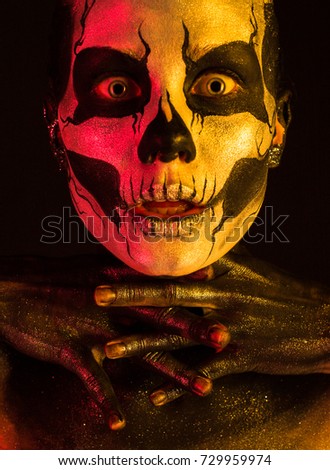 Isolated on black, vertical closeup picture, toned red and yellow, beautiful young blonde caucasian woman with scull body art, grey eyes, amazed