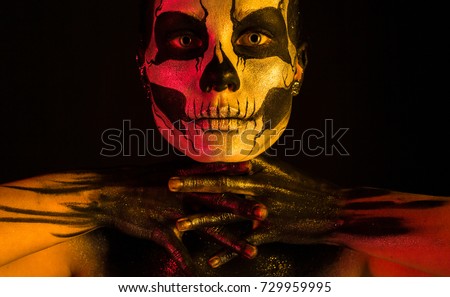 Isolated on black, closeup picture, toned red and yellow, beautiful young blonde caucasian woman with scull body art, grey eyes, look at camera
