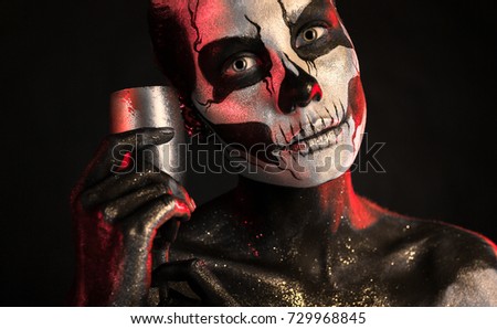 Isolated on black, closeup picture, toned red and white, beautiful young blonde caucasian woman with scull body art with wine glass in hand, grey eyes, look at camera