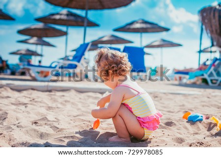 Little girl in pink swimsuit is playing in water