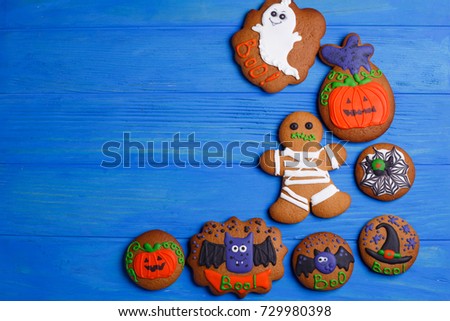 Halloween cookies with funny decorations made of confectionery mastic on blue wooden kitchen table, copy space