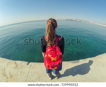 Girl with a red backpack on the beach