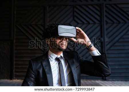 afro businessman playing virtual reality simulation against a dark background
