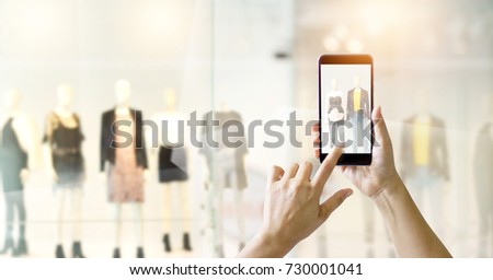 Hands using mobile smart phone and take a photo in display view of a clothing store,  shopping online concept
